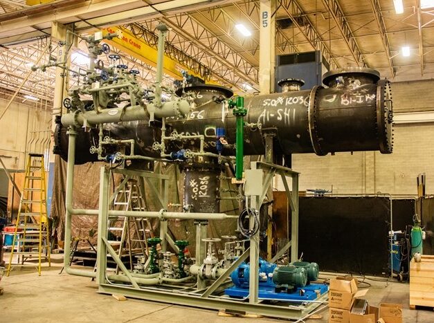 Pressure vessel mounted on a custom fabricated process skid inside Alps Welding's shop.