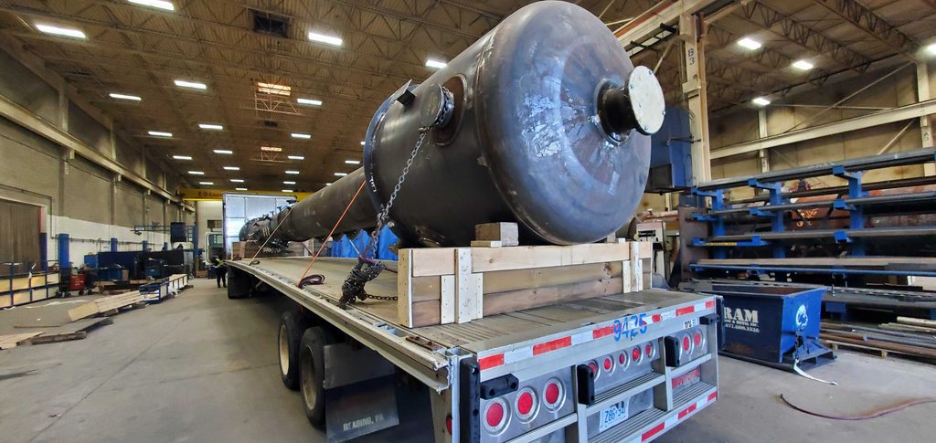 20260828_091126 Angled view of a carbon steel custom pressure vessel head and capped nozzle on a flatbed trailer