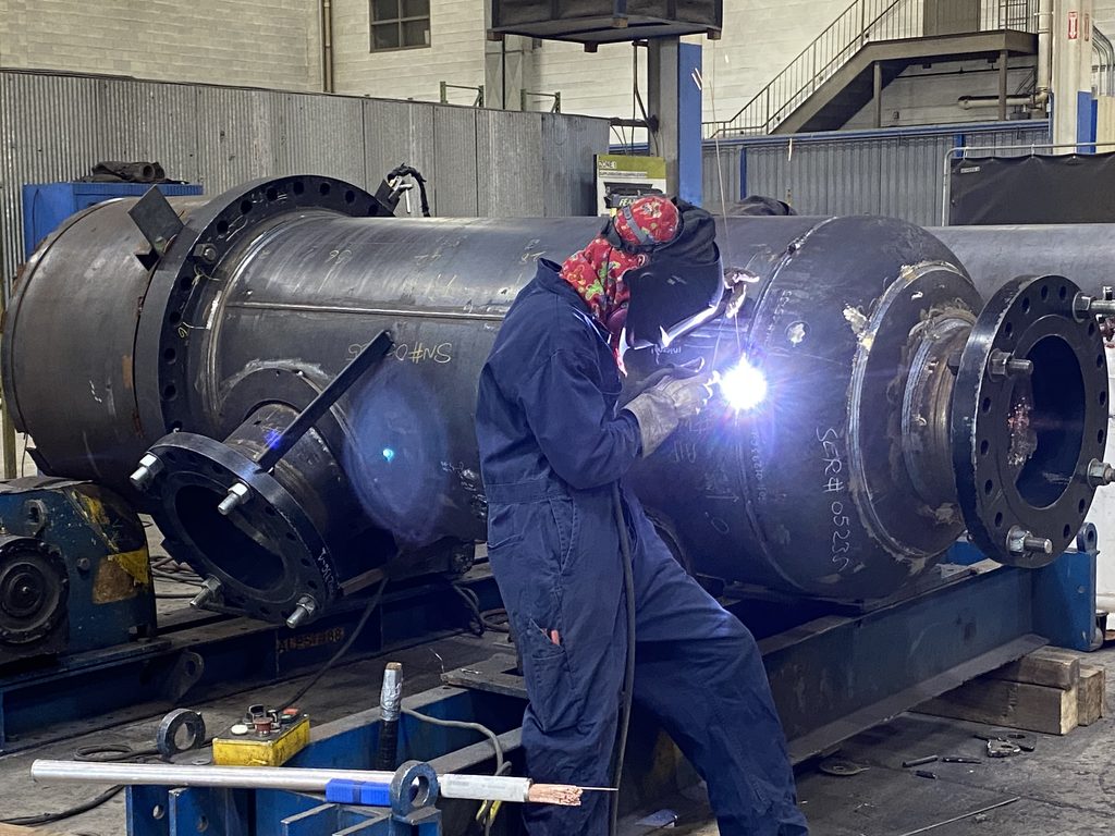 A welding worker is welding a custom pressure vessel at Alps Welding's shop.