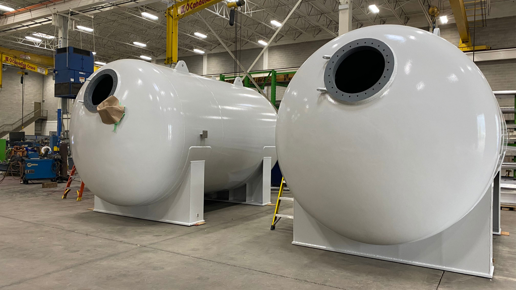 921 new blog Two white horizontal water treatment vessels with flanged openings and support saddles in the Alps Welding shop.